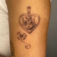 a cat in a heart with a clover tattoo on its leg, next to a shamrock