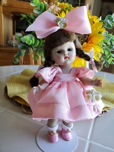 a doll is sitting on a table with flowers in the background