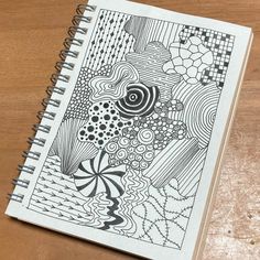 a spiral notebook with an abstract design on the front and back cover, sitting on a wooden table