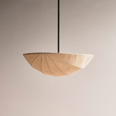 a wooden bowl hanging from a black metal hook on a white wall with light colored walls behind it