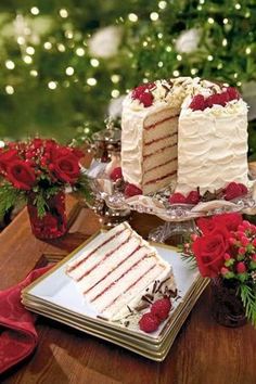 a table topped with two cakes covered in white frosting and red roses next to each other