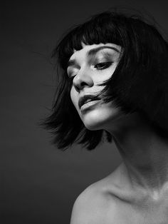 a woman with black hair and white makeup is posing for the camera, her eyes are closed