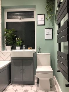 a white toilet sitting next to a bath tub under a window with plants on it