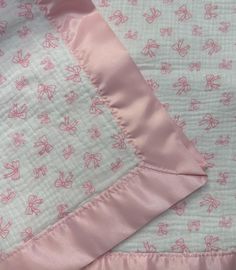 a pink and white quilted blanket with flowers on it