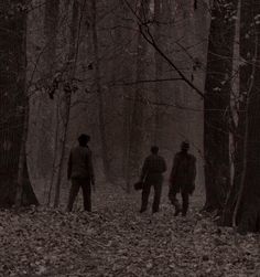 three people walking through the woods in the rain