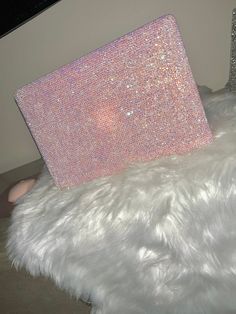 a pink and silver pillow sitting on top of a white fur covered floor next to a computer monitor