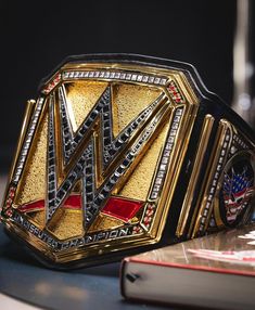 a gold and black wrestling ring sitting on top of a table next to a book