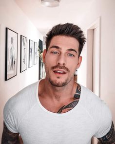 a man with tattoos on his arm and chest standing in front of a mirror looking at the camera