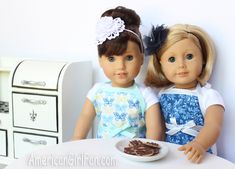 two dolls sitting next to each other at a table with food in front of them