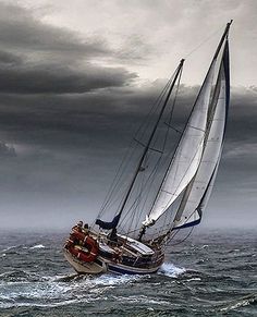 a sailboat in the middle of an ocean under a cloudy sky with dark clouds