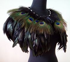 a black mannequin with peacock feathers on it's neck and beads in the center