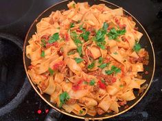 a plate full of pasta with meat and parsley on top, sitting on a black surface