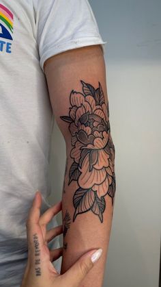 a woman's arm with a flower tattoo on the left side of her arm