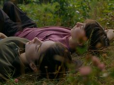 two people laying on the ground in tall grass