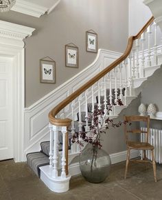 there is a vase with flowers on the floor in front of the stair case and chair