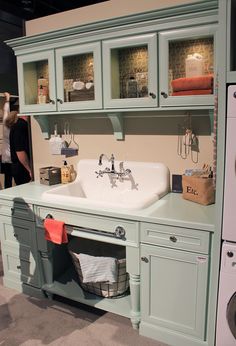 a bathroom sink sitting under a cabinet next to a washer and dryer machine