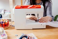 a woman is working on sewing machine with scissors and thread spools in front of her