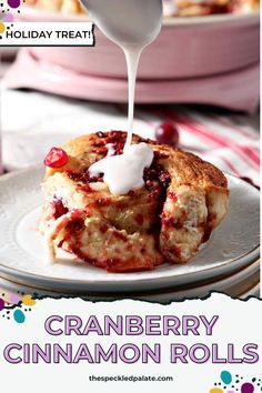 cranberry cinnamon rolls on a plate with icing being drizzled over them