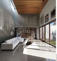 a living room filled with white furniture and lots of books on the shelves next to windows