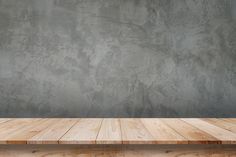 an empty wooden table in front of a concrete wall