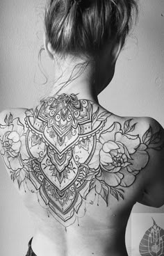 the back of a woman's neck with flowers and leaves tattooed on her chest