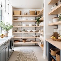 a kitchen filled with lots of open shelving next to a sink and counter top