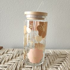 a glass jar with flowers painted on the side and a straw sticking out of it