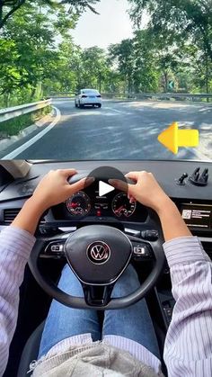 a person driving a car on a road with trees in the background and yellow arrows pointing up