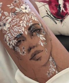 a woman's face is covered with white paint and has flowers painted on it