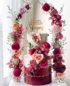 a three tiered cake decorated with flowers and greenery