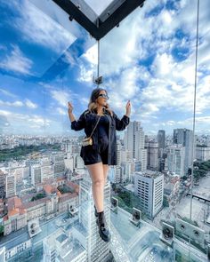 a woman standing on top of a glass floor in front of a cityscape