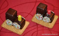 two pieces of chocolate with sprinkles on them sitting on a red surface