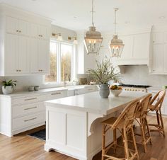 a kitchen filled with lots of white cabinets and counter top next to a dining room table