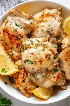 a white bowl filled with chicken and lemon slices