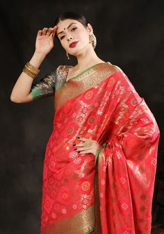 a woman in a red and gold sari with her hands on her head, posing for