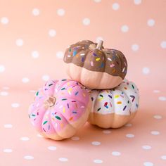 three donuts with sprinkles are stacked on top of each other in front of a pink background