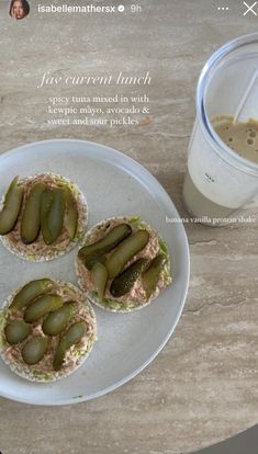 three sandwiches with pickles are on a plate next to a cup of coffee and a glass of milk