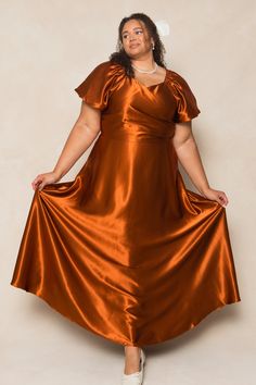 a woman in an orange dress poses for the camera with her hands on her hips