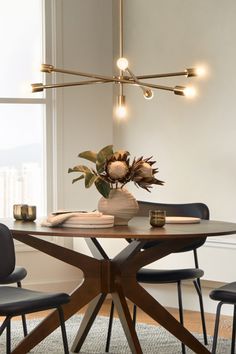 a dining room table with chairs and a vase filled with flowers on top of it