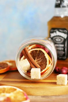 a glass jar filled with orange slices and cinnamon on top of a wooden cutting board