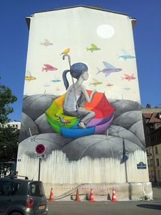 a large mural on the side of a building with a woman sitting in an umbrella