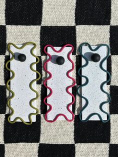 three cell phones sitting on top of a checkered cloth