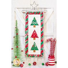 a wall hanging decorated with christmas trees and candy canes next to a small tree