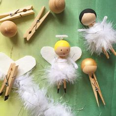 several wooden peg dolls and other craft items on a green surface with white feathers around them