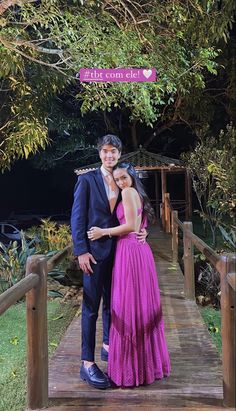 a man and woman standing on a wooden bridge