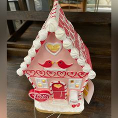 a red and white gingerbread house on a wooden table