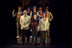 a group of men standing next to each other on top of a wooden floor in front of a stage