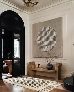 a living room filled with furniture and a large painting on the wall above it's doorway