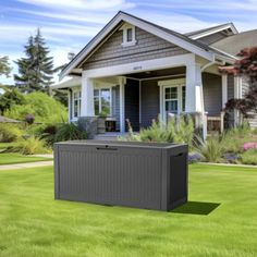 an outdoor storage box sitting in the middle of a lawn next to a large house