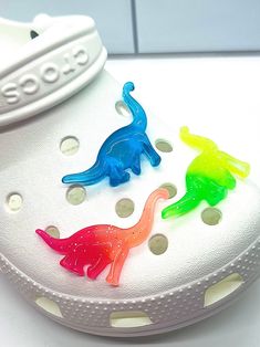 three different colored plastic shoes with holes in the soles on a white counter top